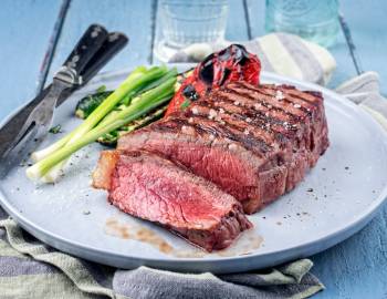 Closeup of a sliced steak served on a plate with vegetables