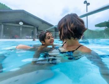 A mother and son swimming in an outdoor hot springs pool