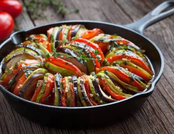 A traditional ratatouille dish served in a cast iron pan on a table