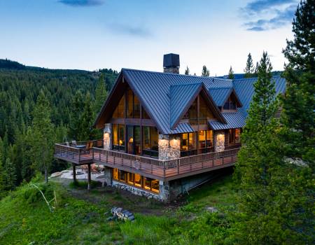 Brown two-story cabin with a brown roof surrounded by trees in Yellowstone at dusk.