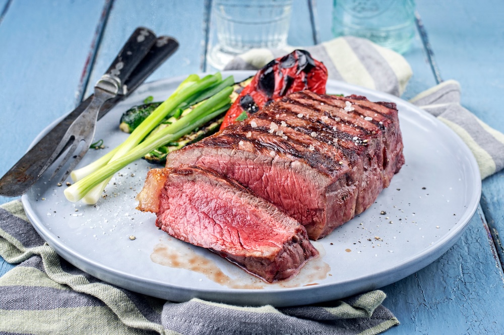 Closeup of a sliced steak served on a plate with vegetables