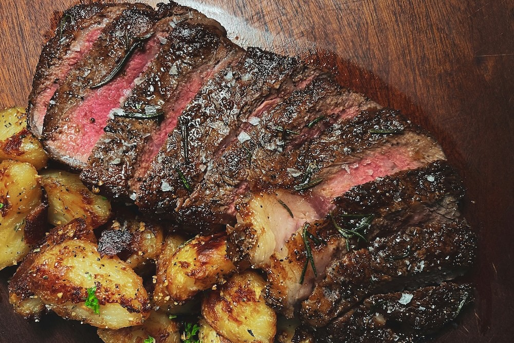 Steak and potatoes on a chopping block