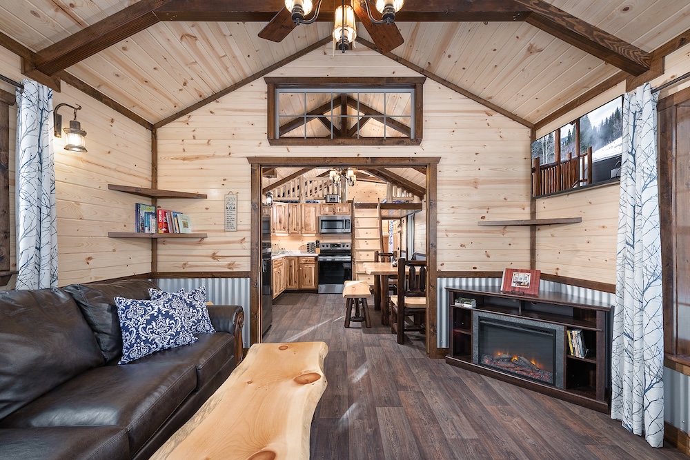 Vacation rental cabin interior with sofa, fireplace, and full kitchen