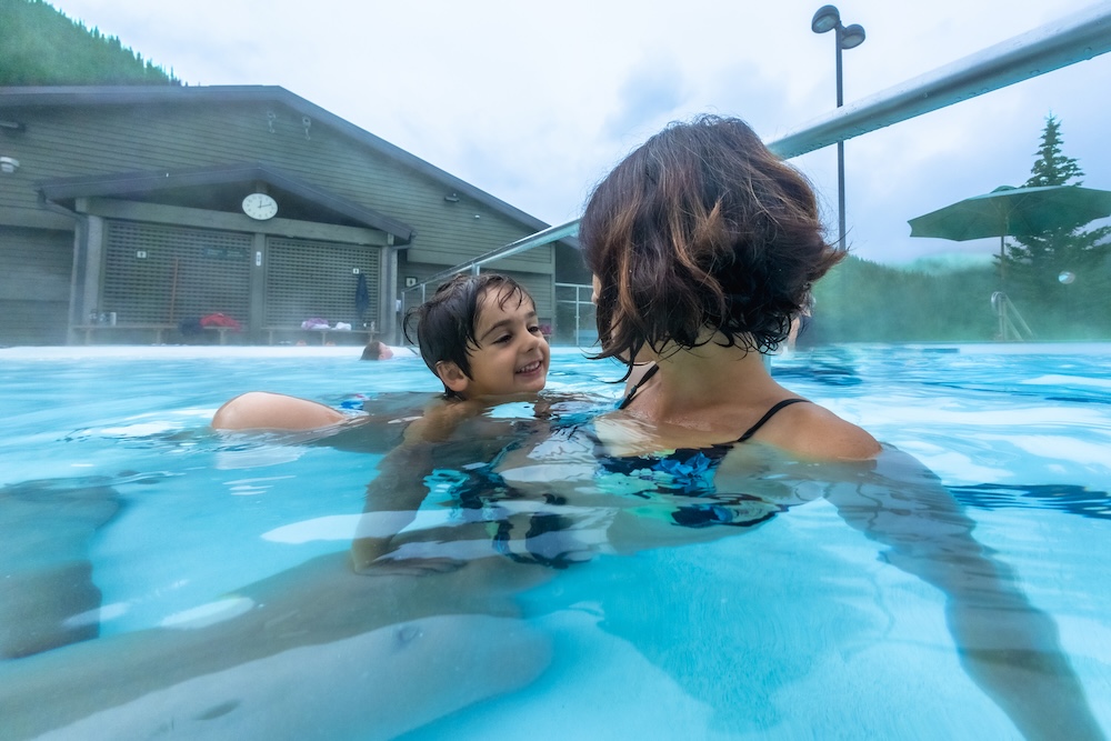 A mother and son swimming in an outdoor hot springs pool