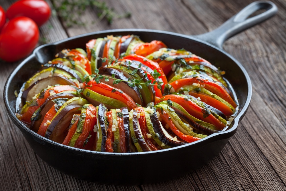 A traditional ratatouille dish served in a cast iron pan on a table