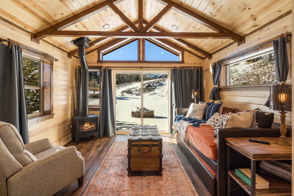 Vacation rental cabin interior with sofa, fireplace, and picture window views