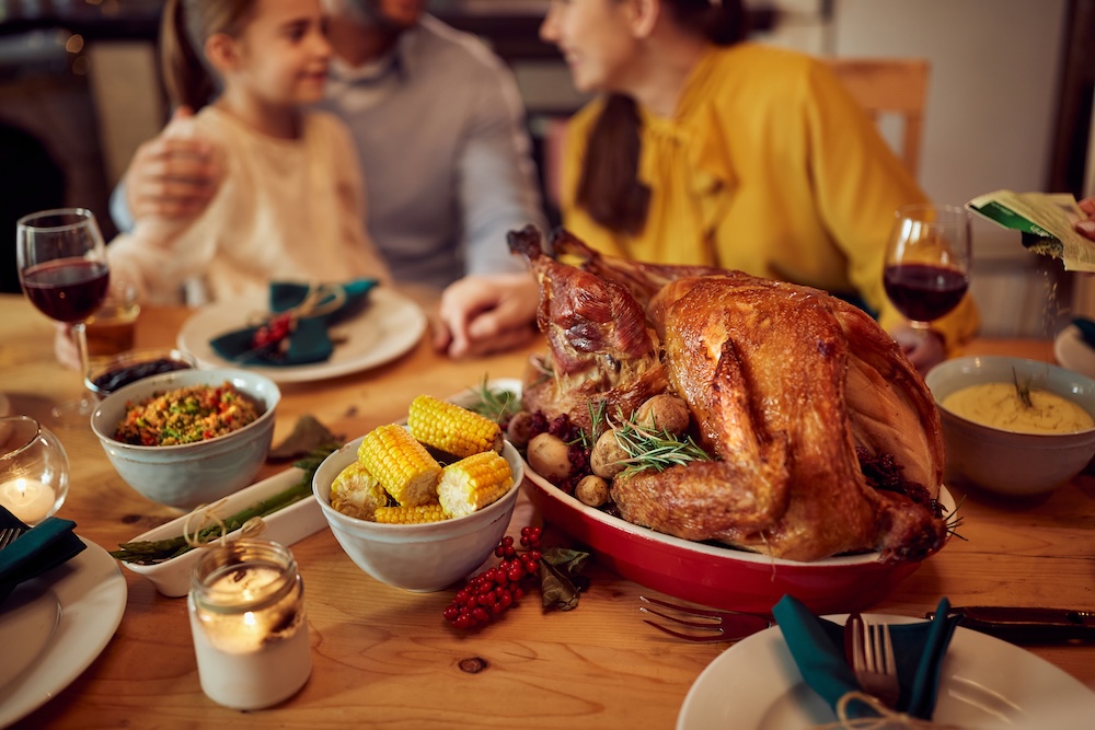 A Thanksgiving turkey and various sides on a table with a family talking in the background